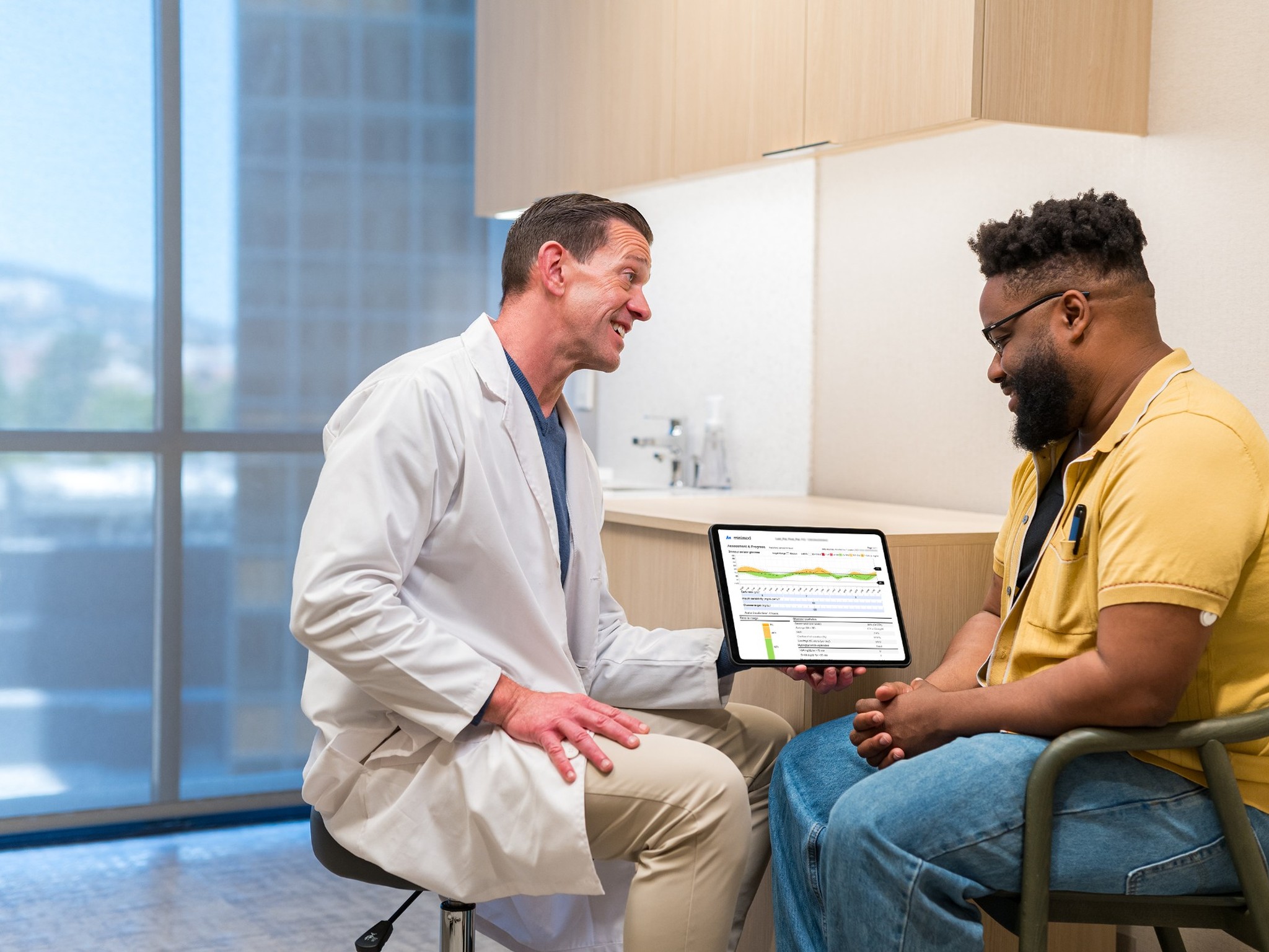 Healthcare provider reviews glucose management data on a tablet with a patient during a consultation in a medical office