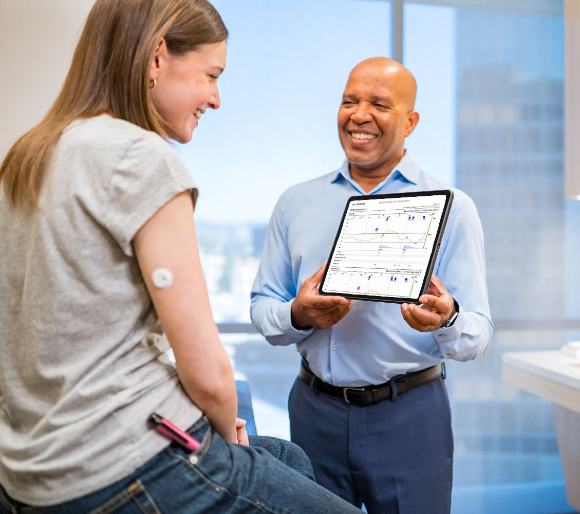 Healthcare professional reviewing glucose and insulin therapy data on a tablet with a patient.